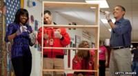 Michelle and Barack Obama help stain a bookshelf