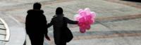 A couple walking in Beijing on Valentines Day carrying some pink balloons