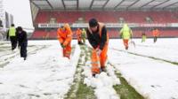 Snow being cleared off a football pitch