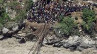 Rescuers attempting to use makeshift bridges to help stranded pilgrims in India