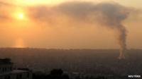 Smoke rises behind buildings from the site of an explosion in Beirut's southern suburb