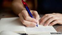 Close up of hands writing in a book with a pen
