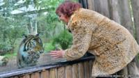 Woman in animal print near to a tiger