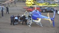 An injured spectator is wheeled by paramedics to a helicopter.