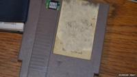 A grey Nintendo cartridge. The label is ripped off and Mario has been written on in pen.