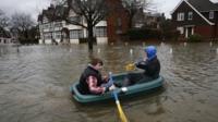 Two boys in a boat in a flooded street