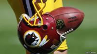 A player carries a Redskins helmet with a football in it.