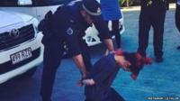 Police officer putting handcuffs on Lily Allen