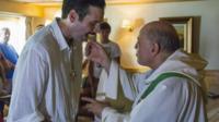 Chris Catrambone and priest at the mass on board the Phoenix