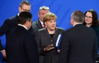 Angela Merkel, surrounded by cabinet ministers, is handed a report by Germany's council of economic advisers (12 Nov)