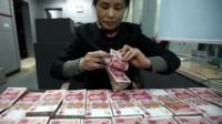 A clerk counts Chinese currency