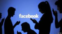 Silhouettes in front of Facebook logo