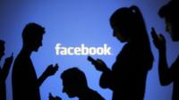 People posing in front of Facebook projection