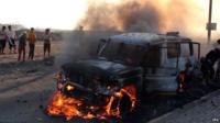 Yemenis gather beside a burning vehicle allegedly belonged to Houthi fighters following clashes with tribal militiamen loyal to Yemeni president Hadi in the southern port city of Aden on 26 March, 2015.