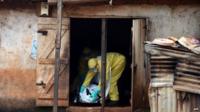 A file photo taken on November 12, 2014 shows health workers from Sierra Leone"s Red Cross Society Burial Team 7 preparing to carry a corpse out of a house in Freetown.