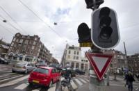 Cars and bicycles improvise crossing an intersection as traffic lights are off during a power outage in Amsterdam, Netherlands, Friday, 27 March 2015
