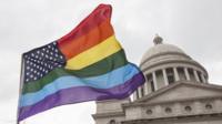 An American flag with rainbow-coloured stripes outside the Arkansas capitol building