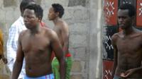 Some students without their shirts get out of a house where they seek refuge after escaping from an attack by gunmen in Garissa, Kenya, 2 April 2015