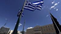 A Greek flag flutters in front of the Greek parliament