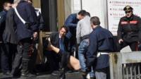 Rescuers and police treat an injured man after a shooting at the Palace of Justice in Milan (9 April 2015)