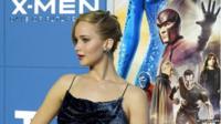 Actress Jennifer Lawrence who plays Mystique standing in front of an X-Men film poster