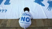 A boy arranges a banner on the ground during a rally organised by the Spring Hunting Out coalition in Valletta (08 April 2015)