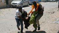 People carry a wounded person at the scene of a car bomb outside the higher education ministry in Mogadishu on Tuesday