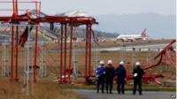 Officials check broken localiser facilities at the Hiroshima airport in Mihara in Hiroshima on 15 April 2015 after an Asiana Airlines Airbus A320 aircraft (seen in background) overran a runway at the airport