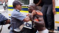 Members of the South African Police Services (SAPS) try to control a protester after clashes broke out between a group of locals and police in Durban on 14 April 2015