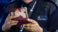 Border Force officer checking passports at Heathrow Airport