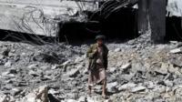 A Houthi rebel walks among the ruins of a stadium allegedly destroyed by a Saudi air strike in Sanaa, Yemen (12 April 2015)