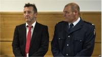 Phil Rudd and policeman in court in Tauranga, New Zealand (21 April 2015)