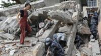 A tourist watches soldiers searching a collapsed house in Kathmandu