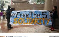 Protestors hold up a "Free The Five" banner