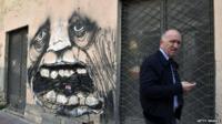 A man walks past abandoned businesses in central Athens in April 2015