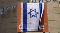 The Orange company logo is seen covered with an Israeli flag at the "Partner Orange" Communications Company"s offices in the city of Rosh Haain, Israel, Thursday, June 4, 2015.