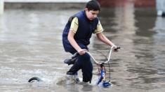 A boy rides a bicycle on a flooded street in Qatar's capital Doha following heavy rainfall on 25 November 2015