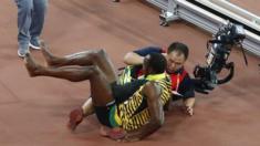 Usain Bolt of Jamaica is knocked over by a cameraman in Beijing, 27 August 2015