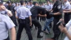 Police scuffle with a protestor outside the municipal government headquarters in Shanghai (27 June 2015)