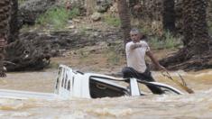 A man tries to save a vehicle from being swept away from water on the Yemeni island of Socotra (2 November 2015)
