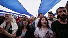 People sing the Greek national anthem under a giant Greek flag during a pro-European demonstration in front of the Greek parliament in Athens on Monday