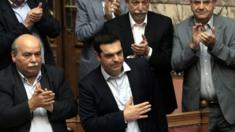 Greek PM Alexis Tsipras (first row, right) reacts after speaking in parliament