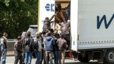 Migrants climb in the back of a lorry in Calais