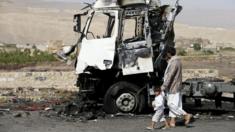 A man and his son walk past a truck hit by a Saudi-led air strike in Yemen's northwestern province of Amran on 29 August