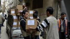 Relief workers unload aid parcels to be distributed at the Palestinian refugee camp of Yarmouk, in Damascus on 11 March 2015