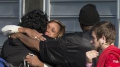 People hug outside the home where police say seven children and one adult were found dead on 6 April 2015