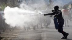 A riot police officer sprays teargas on residents participating in street protests in Burundi