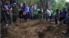 This picture taken on May 2, 2015 shows rescue workers and forensic officials digging out skeletons from shallow graves covered by bamboo at the site of a mass grave at an abandoned jungle camp in the Sadao district of Thailand's southern Songkhla province bordering Malaysia