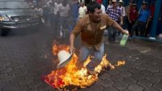 A protester buns a flag of Nicaragua's ruling party during a rally against a planned canal