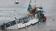Rescuers check the wreckage of a people smuggler's boat seen half submerged after being towed near the coast of Puger village in East Java province, 2011